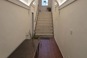 A staircase with a handrail, a potted plant at the top, and a door on the left. - Ancient Convent - Casoni House (Recanati)