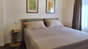 Een hotelkamer met een bed, nachtkastje en twee ingelijste foto's aan de muur.