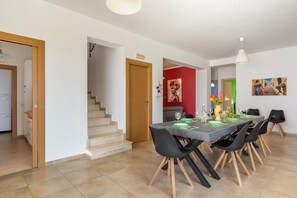 Ein moderner Essbereich mit einem für sechs Personen gedecktem Tisch, einer Treppe und einer roten Akzentwand.