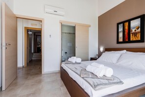 A hotel room with a bed, towels, a painting, and a bathroom door. - Villa Giardino Sul Mare - Scicli (Scicli)