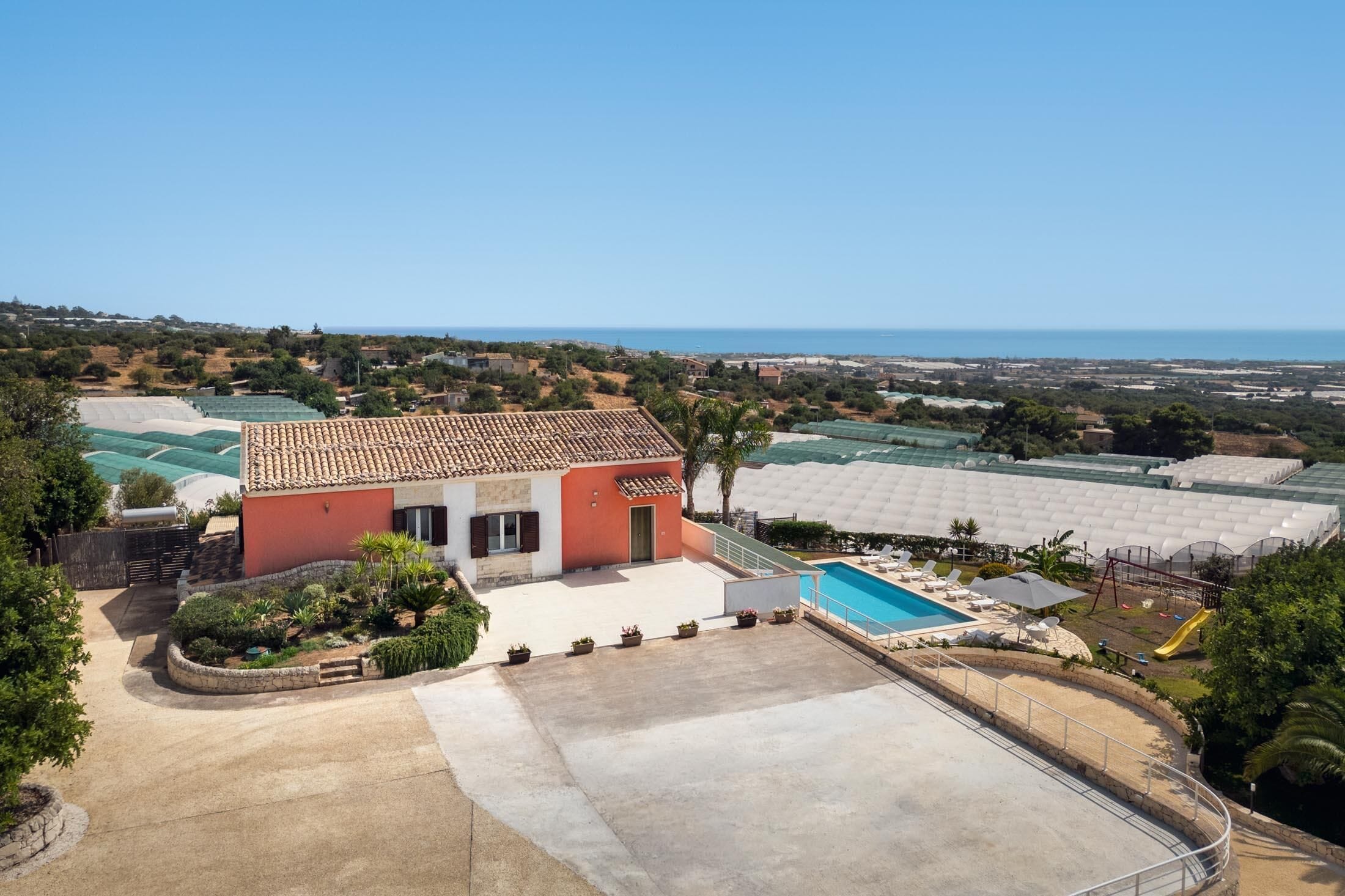 A residential property with a swimming pool, a garden, and a view of the sea.