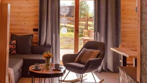 A cozy room with a sofa, a rocking chair, a small table with cups, and a vase of flowers. - Cottage With Private Hot Tub in Stecowka (Istebna)