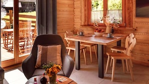 A wooden cabin interior with a dining area, a sofa with a cushion, and a table with a vase of flowers. - Cottage With Private Hot Tub in Stecowka (Istebna)