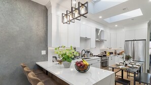 Une cuisine moderne dotée d’un îlot central, de meubles blancs et d’un coin repas avec une table dressée pour quatre personnes.