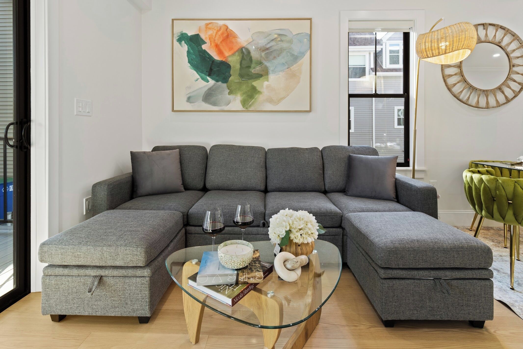 A modern living room with a sectional sofa, a glass coffee table, and a decorative wall piece.