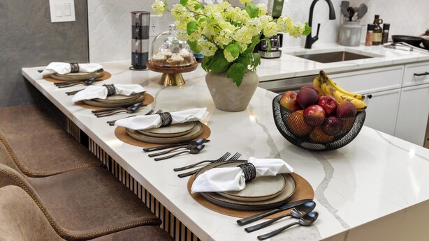 Une table à manger dressée avec des assiettes, des couverts et un vase de fleurs.