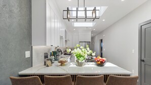 Une cuisine moderne dotée d’un îlot central, de luminaires suspendus et donnant sur l’espace repas.