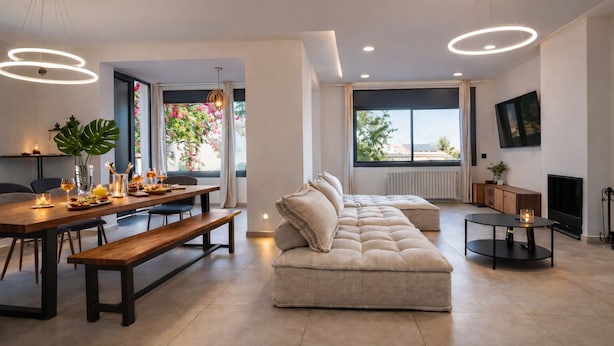 A modern living room with a sofa, dining table, and a fireplace. - Villa Avril · 7 bedrooms, large pool, and unique terraces near Sitges (Olivella)