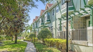 A row of townhouses with green accents, a paved pathway, and well-maintained landscaping.