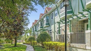 A row of townhouses with a pathway, greenery, and a sign indicating availability. - Resort 4BR Townhome | Private Pool Access & Disney Nearby (Orlando)