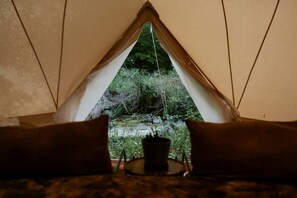 Una tienda de campaña con vistas a un paisaje natural a través de una abertura triangular.