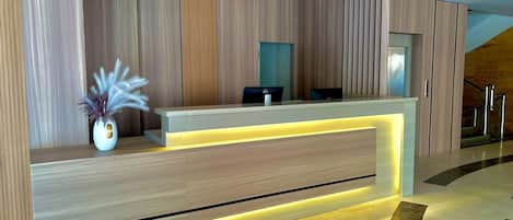 A reception desk with a modern design, featuring a wooden finish and integrated lighting.