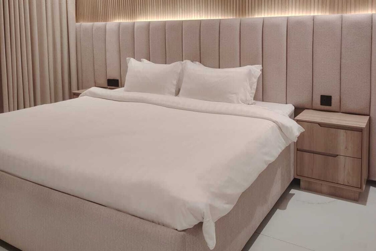 Un dormitorio moderno con una cama grande, un cabecero de madera y una mesita de noche.