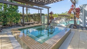 Ein Poolbereich mit Pergola, Liegestühlen und einem kleinen Wasserfall.