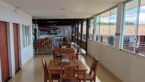 A corridor with wooden tables and chairs, a sign indicating a reserved suite, and a view of the outside through large windows.