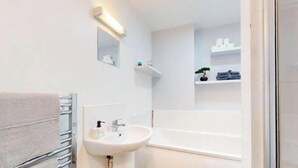 A bathroom with a sink, mirror, towel rack, and shelves with toiletries. - Affordable Luxury At The Heart Of The City (Cardiff)