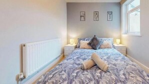 A bedroom with a bed, bedside tables, a radiator, and artwork on the wall. - Affordable Luxury At The Heart Of The City (Cardiff)