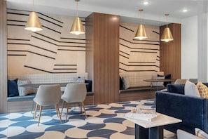 Ein stilvoller Lounge-Bereich mit einer Couch, Sesseln, einem Tisch und Pendelleuchten.