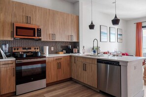 Eine moderne Küche mit Holzausstattung, Edelstahlgeräten, einem Backofen und einem Geschirrspüler.