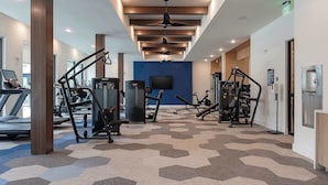 Ett gym med löpband, styrketräningsmaskiner och en blå vägg i bakgrunden.