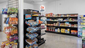En mataffärs interiör med hyllor fyllda med snacks, drycker och hushållsartiklar.