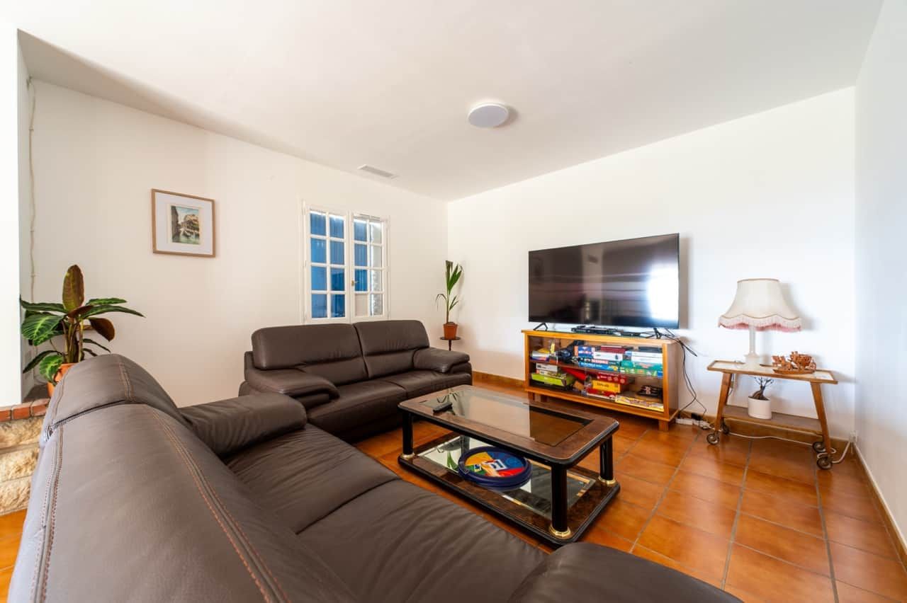 A living room with a sofa, a coffee table, a television, and a lamp.
