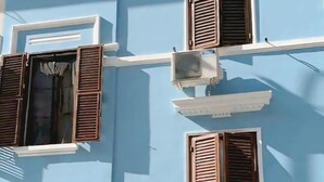 A multi-story building with blue walls, white trim, and wooden shutters on windows. - An oasi of freshness in the hot roman summer (ROME)