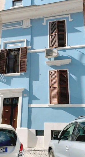 Ein mehrstöckiges Gebäude mit blauen Wänden, weißem Zierrat und Holzfensterläden.