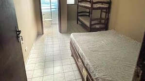 Una habitación con una litera, una puerta que da a un balcón y piso de baldosas.