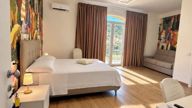 A hotel room with a bed, a desk, a chair, a sofa, and a painting on the wall. - B&B Venere Rooms  (Pimonte)