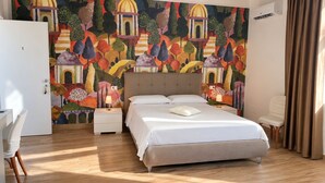 A hotel room with a bed, bedside tables, a desk, and a colorful mural on the wall. - B&B Venere Rooms  (Pimonte)