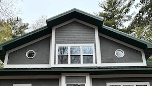 A two-story house with a front door, two windows on the upper floor, and a garage door.