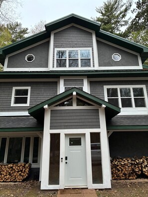 A two-story house with a front door, two windows on the upper floor, and a garage door. - Newly Remodeled Modern house with AC in Crosslake w/ Firepit and Free Wood (Crosslake)