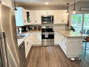 A modern kitchen with white cabinetry, stainless steel appliances, and a granite countertop.