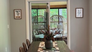 A dining area with a wooden table, chairs, a checkered table runner, and a potted plant.