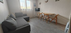 A modern living room with a grey sofa, wooden dining table, and chairs. - Apartment Saint-Aygulf very close to the beach (Fréjus)