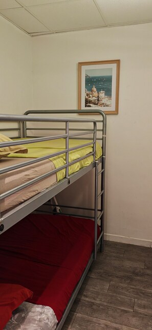 A bunk bed with a red mattress and a green blanket, a framed picture on the wall, and a wooden floor. - Apartment Saint-Aygulf very close to the beach (Fréjus)