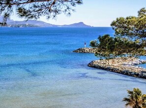 A coastal scene with clear blue water, a rocky outcrop, and a tree. - Vrbo Property (Fréjus)
