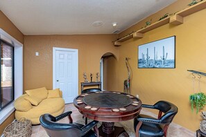 A dining area with a round table, chairs, a sofa, and a door. - Havasu Acoma - Pool, Spa, Game Room, Sleeps 16 (Lake Havasu City)