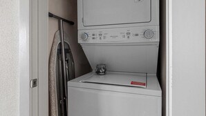 Een kleine wasruimte met een verticaal geplaatste wasmachine en droger.
