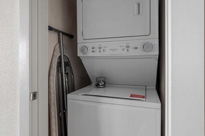 A compact laundry room with a washing machine and dryer stacked vertically. - DallasHaus | Pool & Gym, Love Field (Dallas)
