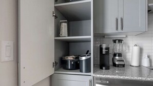 Een keuken met een ingebouwde magnetron, koffiezetapparaat en blender op het aanrecht.