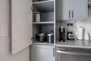 A kitchen with a built-in microwave, a coffee maker, and a blender on the counter. - DallasHaus | Pool & Gym, Love Field (Dallas)
