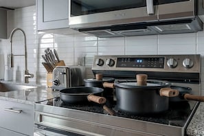 A kitchen with a stainless steel stove, a microwave, a toaster, and a sink. - DallasHaus | Pool & Gym, Love Field (Dallas)
