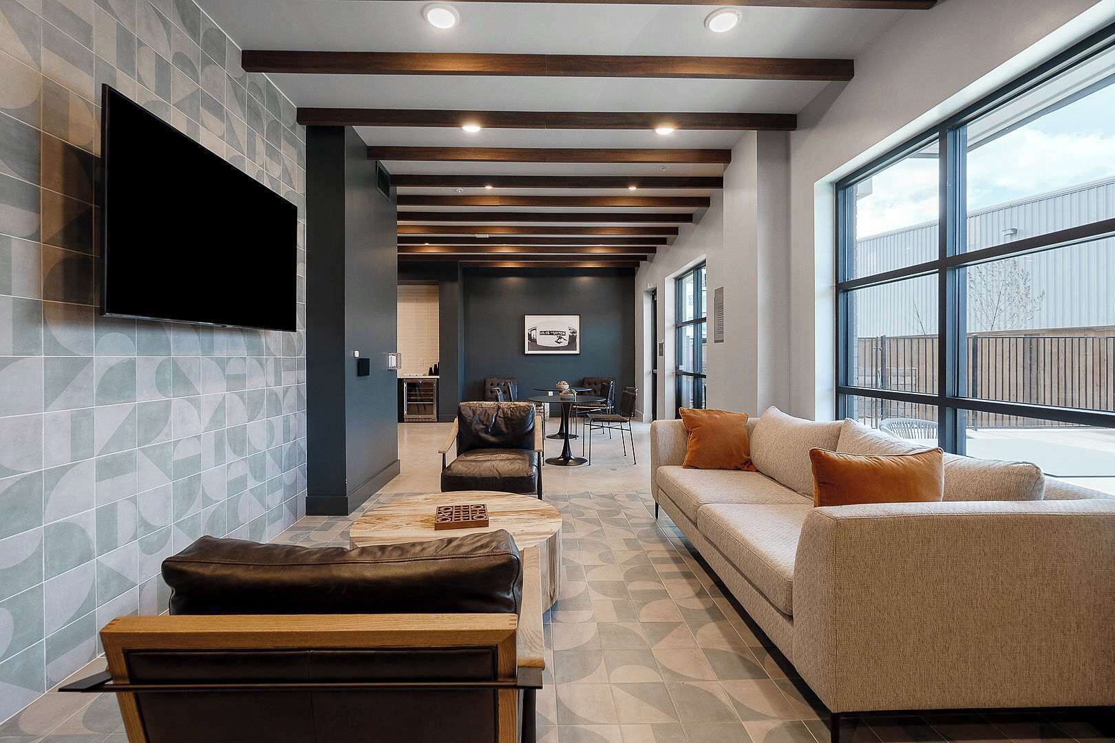 A modern living room with a sofa, armchairs, a coffee table, and a flat-screen TV mounted on the wall.