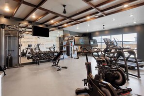 A gym with cardio machines, weightlifting equipment, and a large mirror. - DallasHaus | Pool & Gym, Love Field (Dallas)