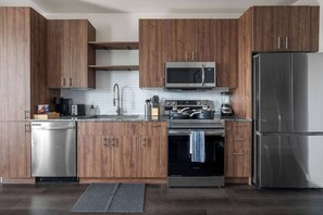Eine moderne Küche mit Holzausstattung, Edelstahlgeräten, einer Mikrowelle, einem Herd und einem Kühlschrank.