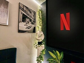 A wall with a framed picture of a tiger on a car, a large red 'N' logo, and a column with greenery.