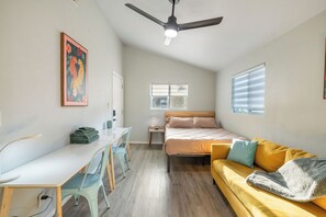 A compact room with a bed, a desk, a chair, a ceiling fan, and a window. - East Austin Retreat w/ Hot Tub & Backyard (Austin)