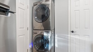 A stacked washer and dryer unit in a hallway with white doors. - East Austin Retreat w/ Hot Tub & Backyard (Austin)